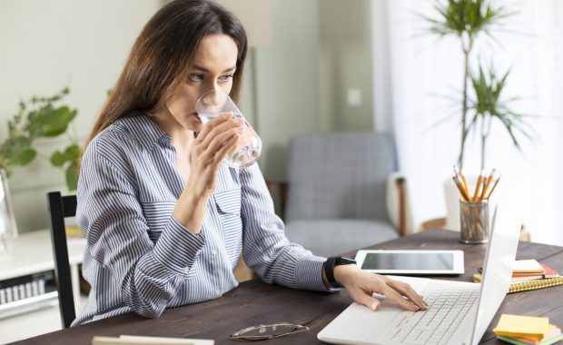 Freelancer young woman working at home and drinking water