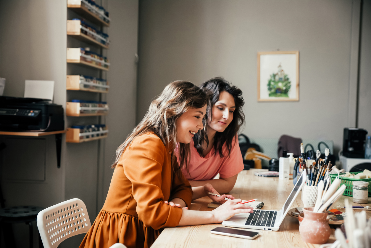 Two women working together on a desk working on a business project.