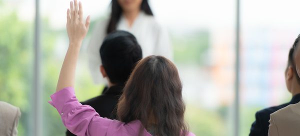 Audience member raising hand during a professional seminar, representing HR copywriter expertise in creating engaging content for human resources communication.