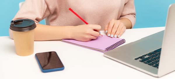 Insurance copywriter planning customer-focused website content and blog strategy at a desk with notebook and laptop